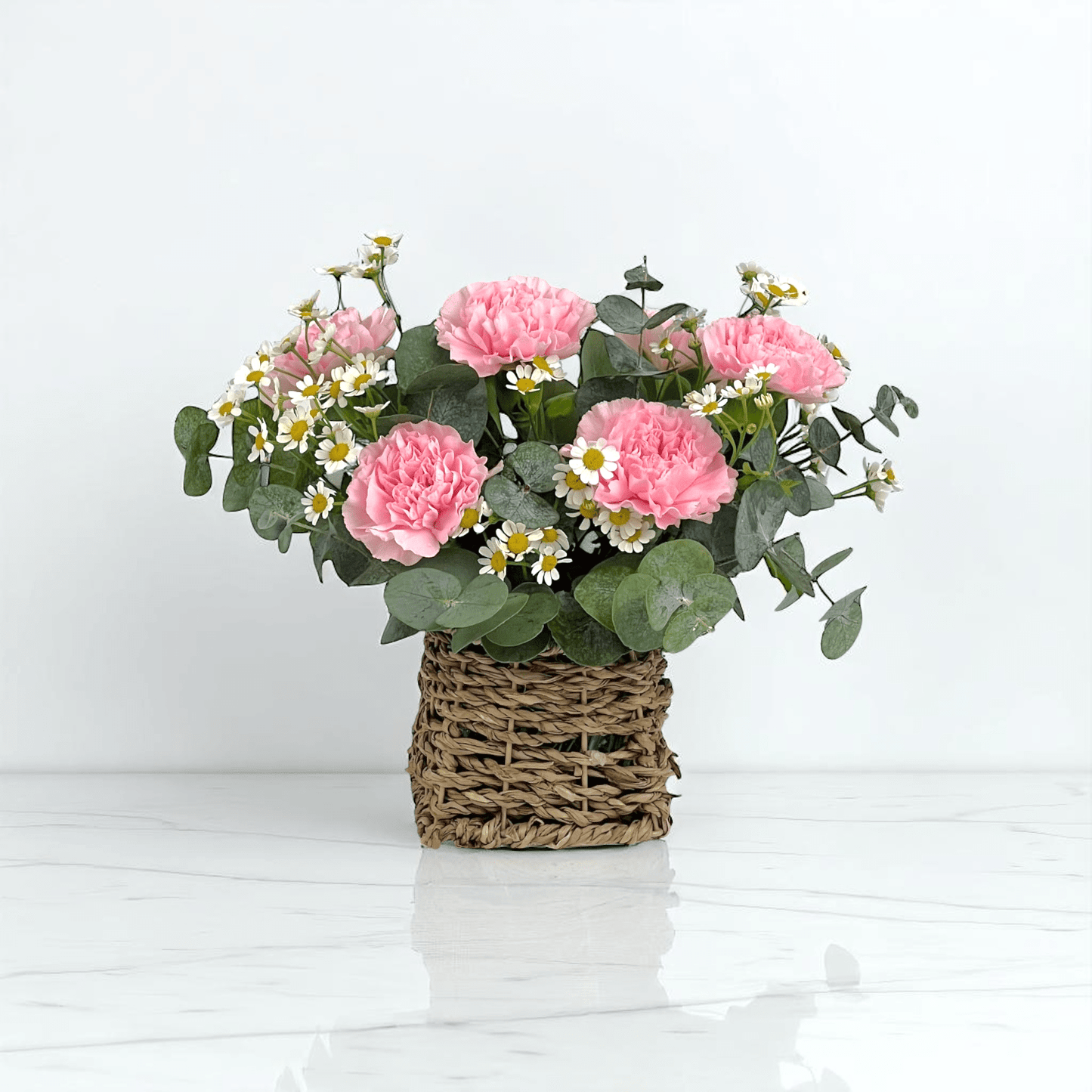 Close-up of Sweet Whisper basket with pink carnations and chamomile, ideal as a gentle and comforting flower gift.