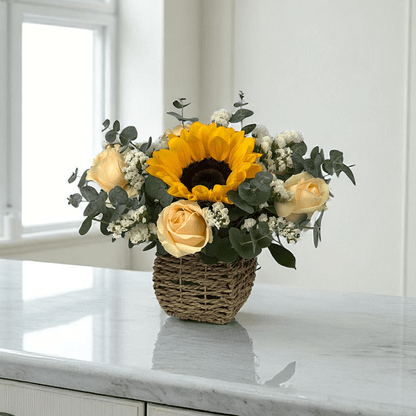 Front view of Golden Shine flower basket with bright sunflowers and peach roses, arranged in a compact decorative basket.