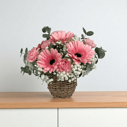 Front view of Sugar Petals flower basket featuring pink gerbera and pink carnations, arranged in a compact round basket.